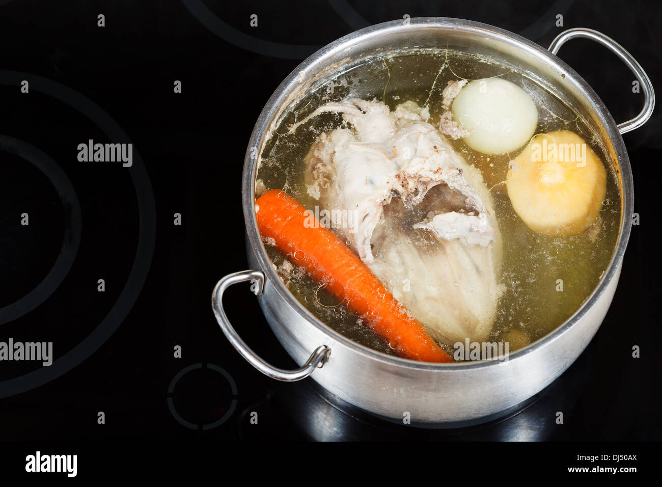 boiling of chicken broth in steel pan on glass ceramic cooker Stock Photo