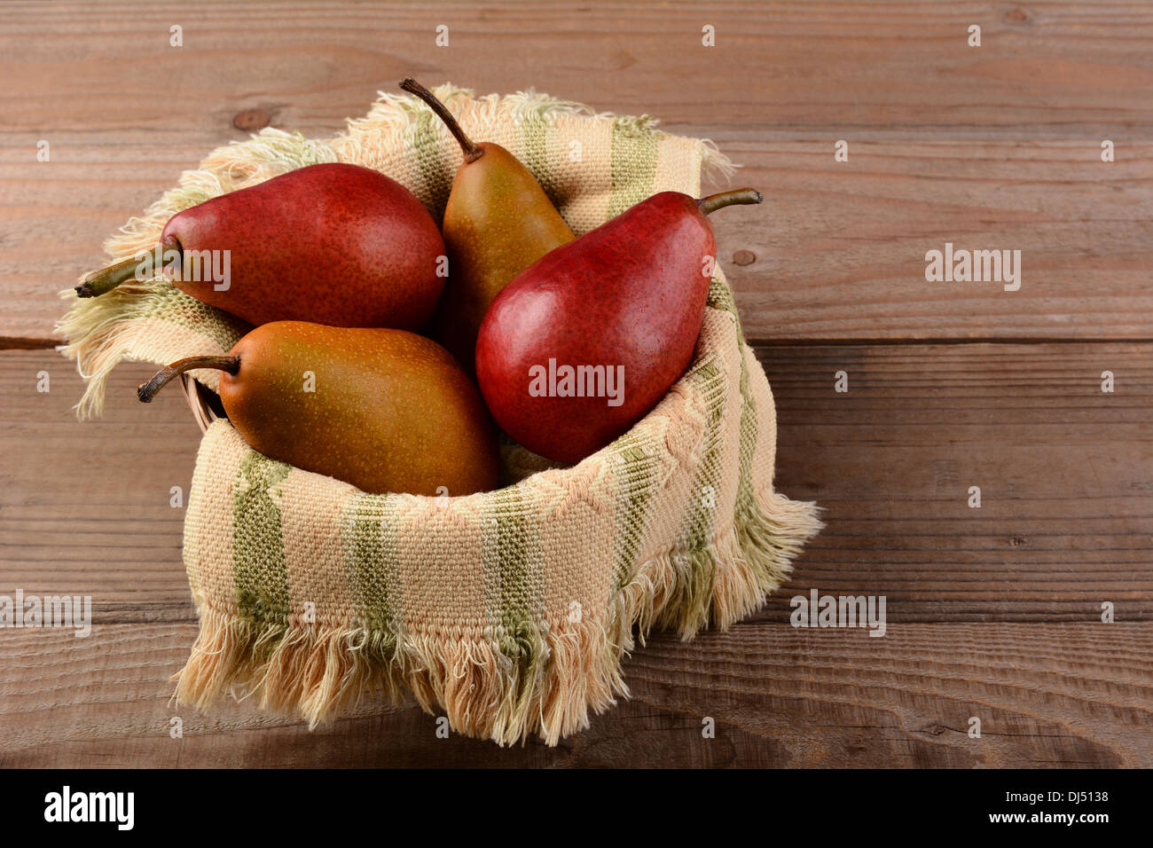 Bosc and Red Pears in a basket on a rustic wooden table. Horizontal format. Stock Photo