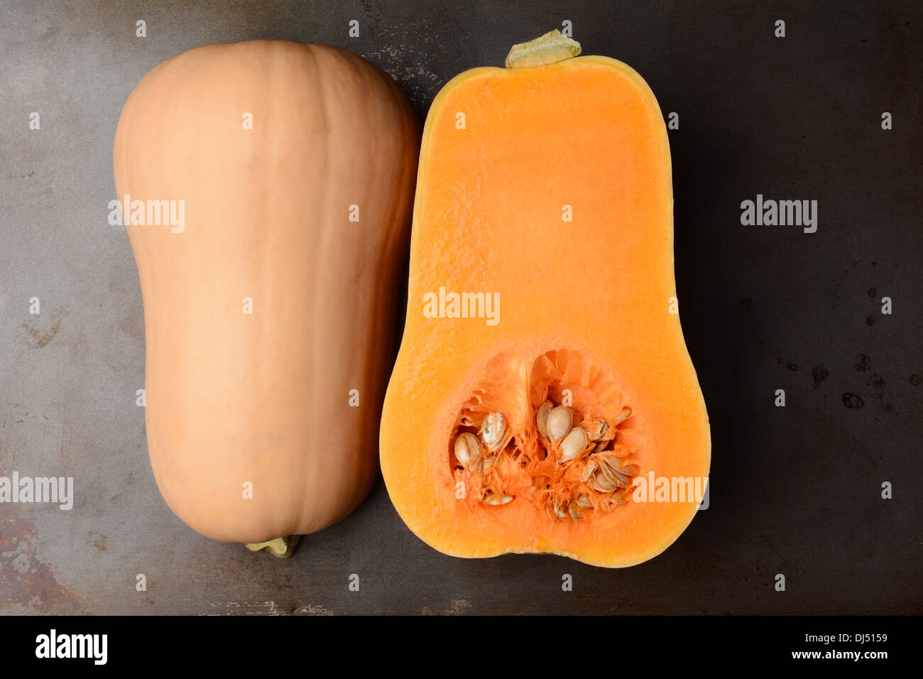Butternut Squash on a metal cooking sheet. The fruit is cut in half showing both the inside and outside. Horizontal format. Stock Photo