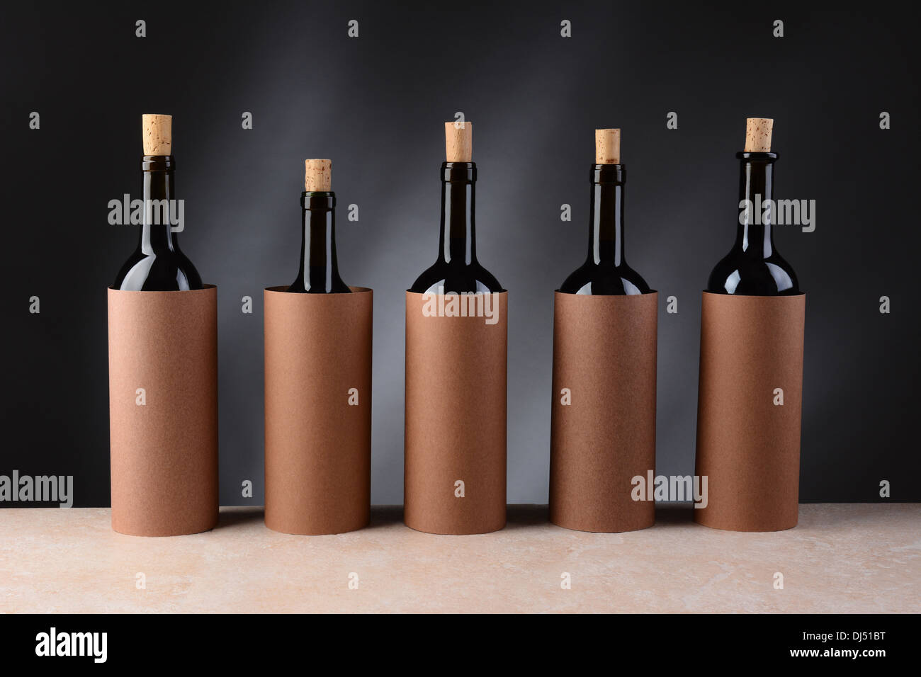 Five different wine bottles set up for a blind wine tasting. The bottles have the corks partially removed Stock Photo