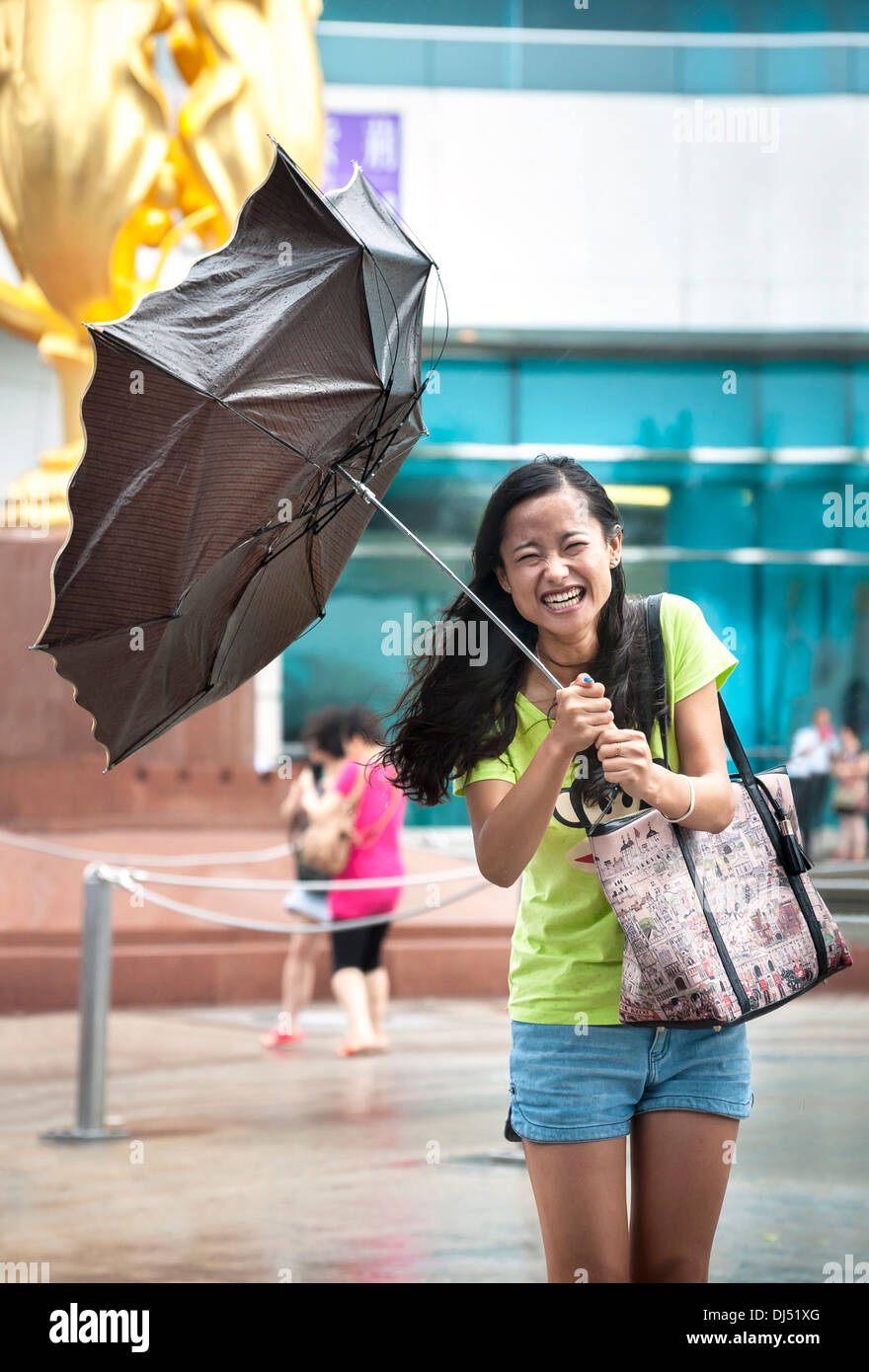 Laughing girl has her umbrella turned inside-out during a typhoon in Hong Kong Stock Photo
