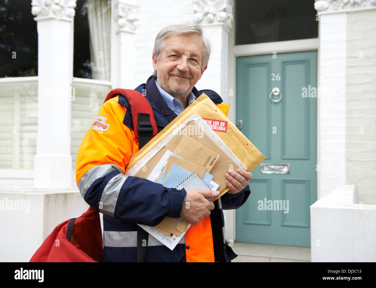 postman delivering mail and packages to domestic home on his morning round Stock Photo