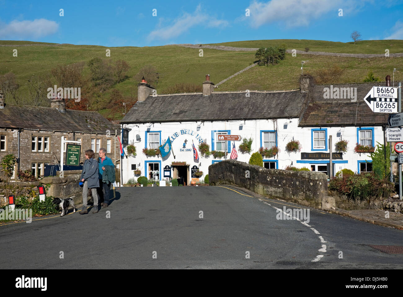 People tourists walkers visitors walking by Blue Bell Inn village pub in winter Kettlewell Wharfedale Yorkshire Dales National Park England UK Stock Photo