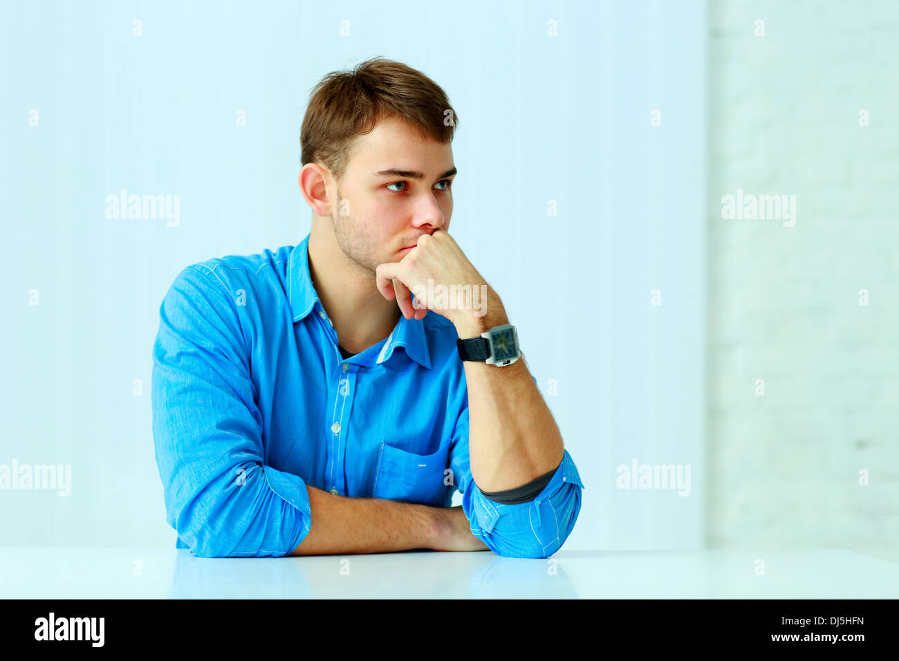 Young pensive businessman sitting at the table at office Stock Photo