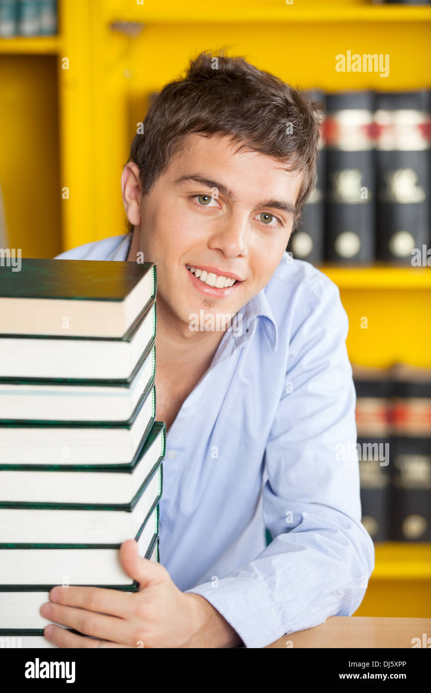 Student With Stacked Books Smiling At Table In Library Stock Photo - Alamy