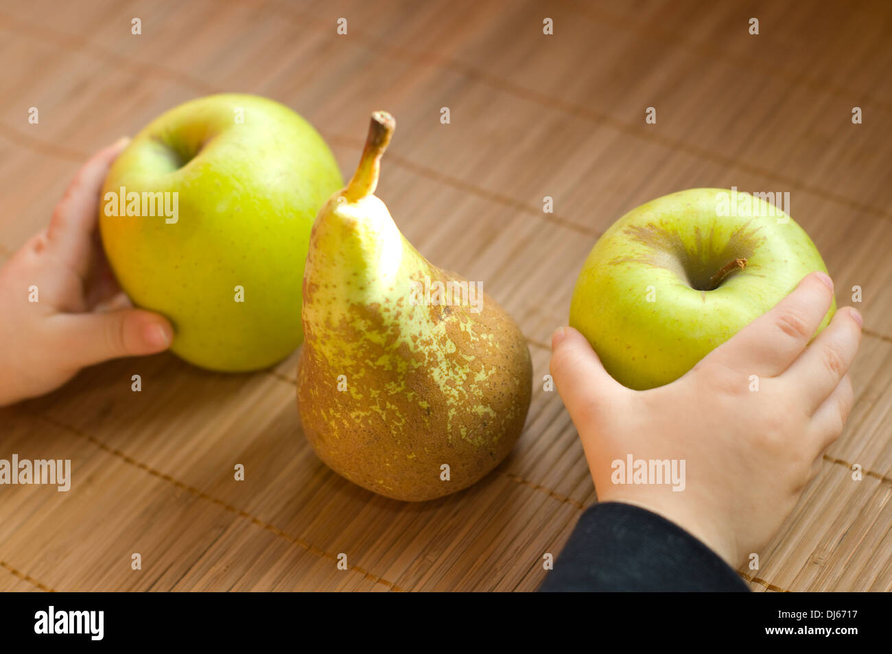 Baby hands catching two apples from the table Stock Photo