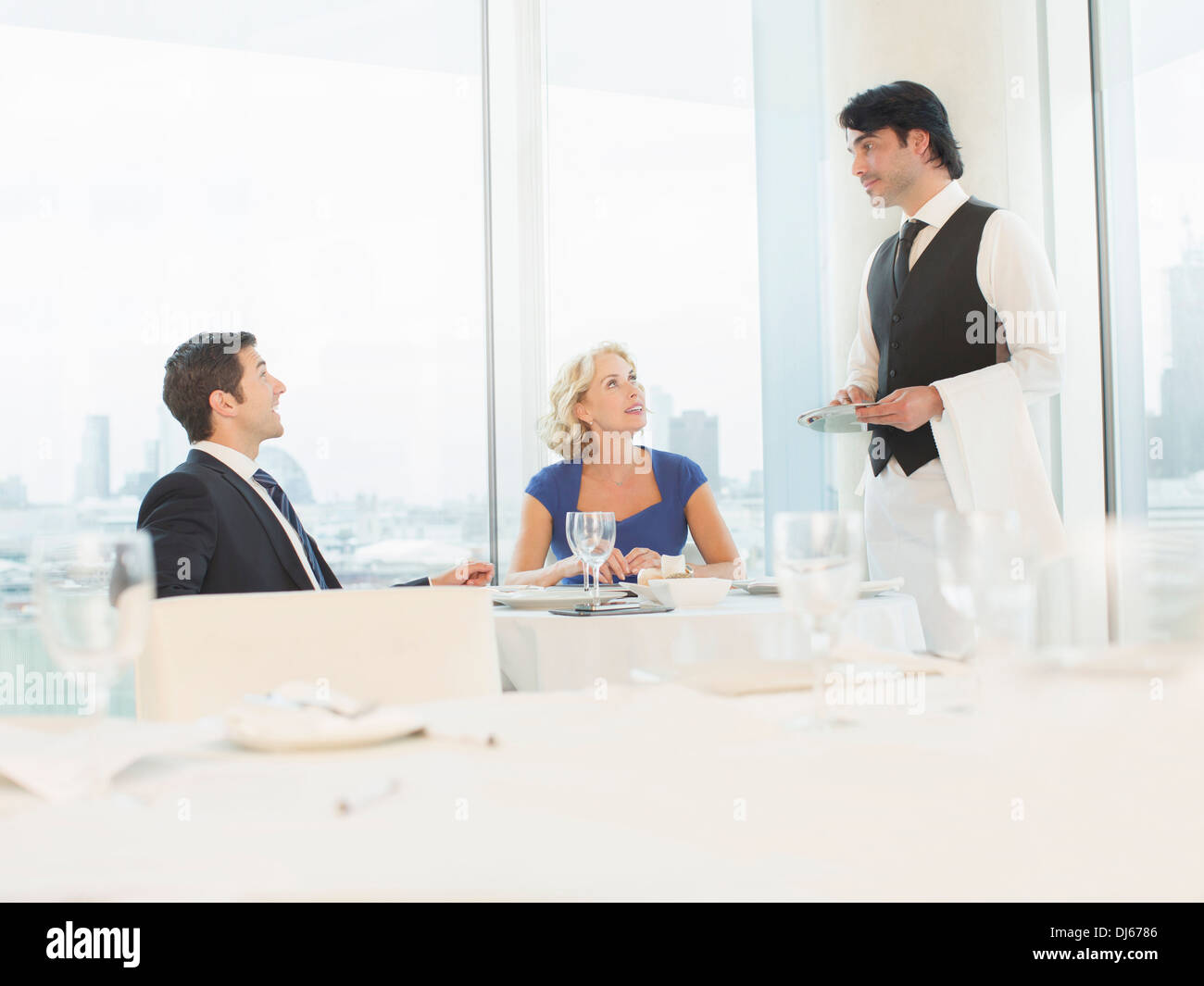 Business people talking to waiter in restaurant Stock Photo