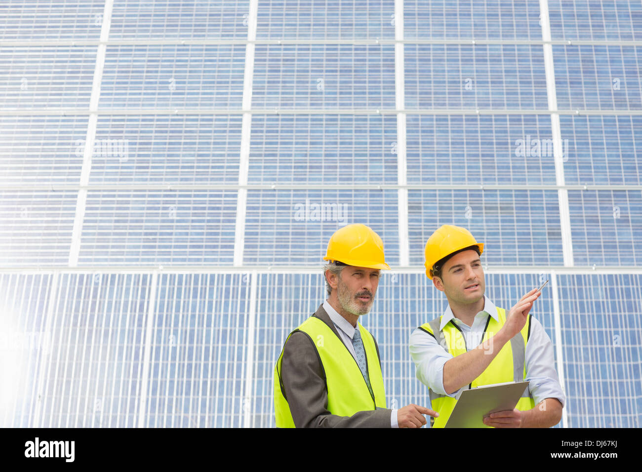 Workers examining solar panels in rural landscape Stock Photo