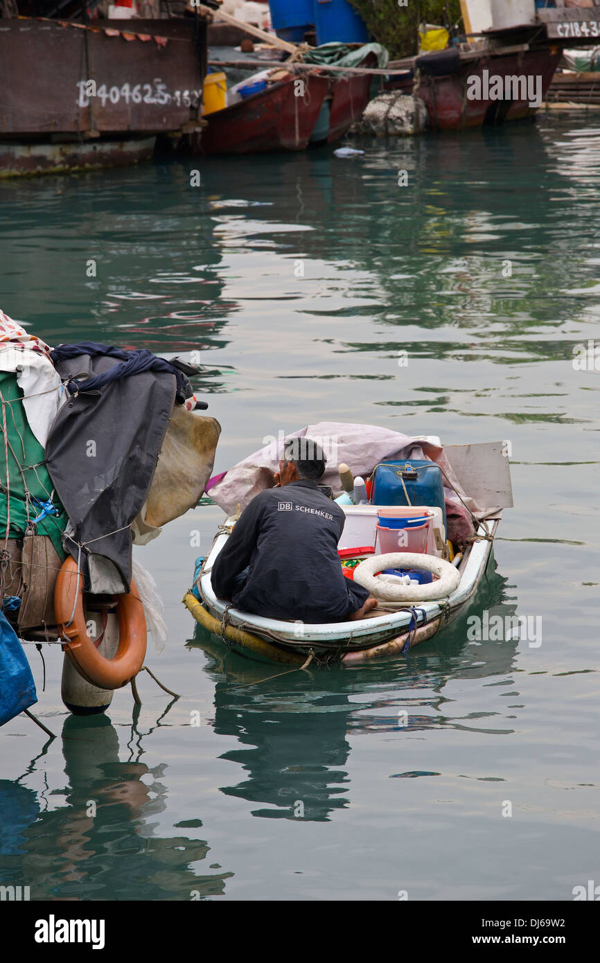 Chinese Man sits on an overloaded dinghy in the Causeway Bay Typhoon
