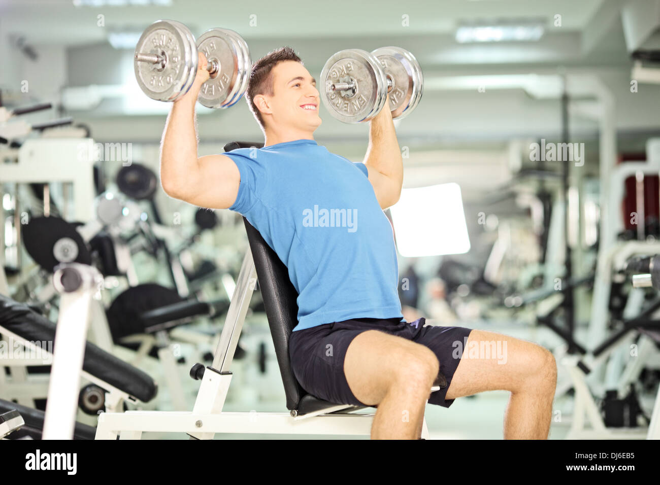Muscular guy lifting weights in a gym Stock Photo Alamy