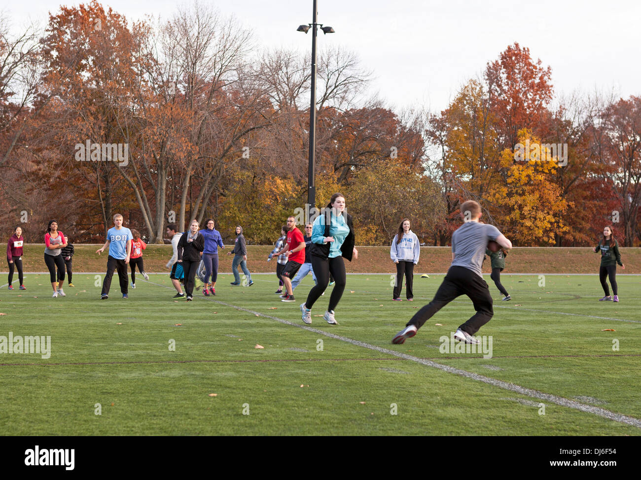 Male and female college students play football together in Boston Stock