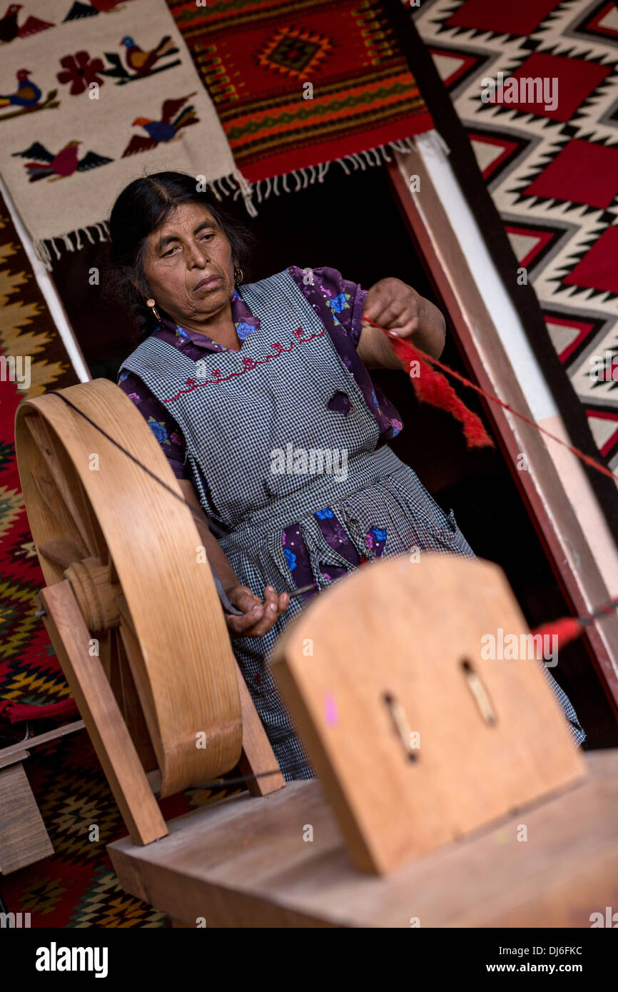 A Zapotec indigenous woman hand spins dyed wool into yarn to be used in weaving traditional carpets in Teotitlan, Mexico. Stock Photo