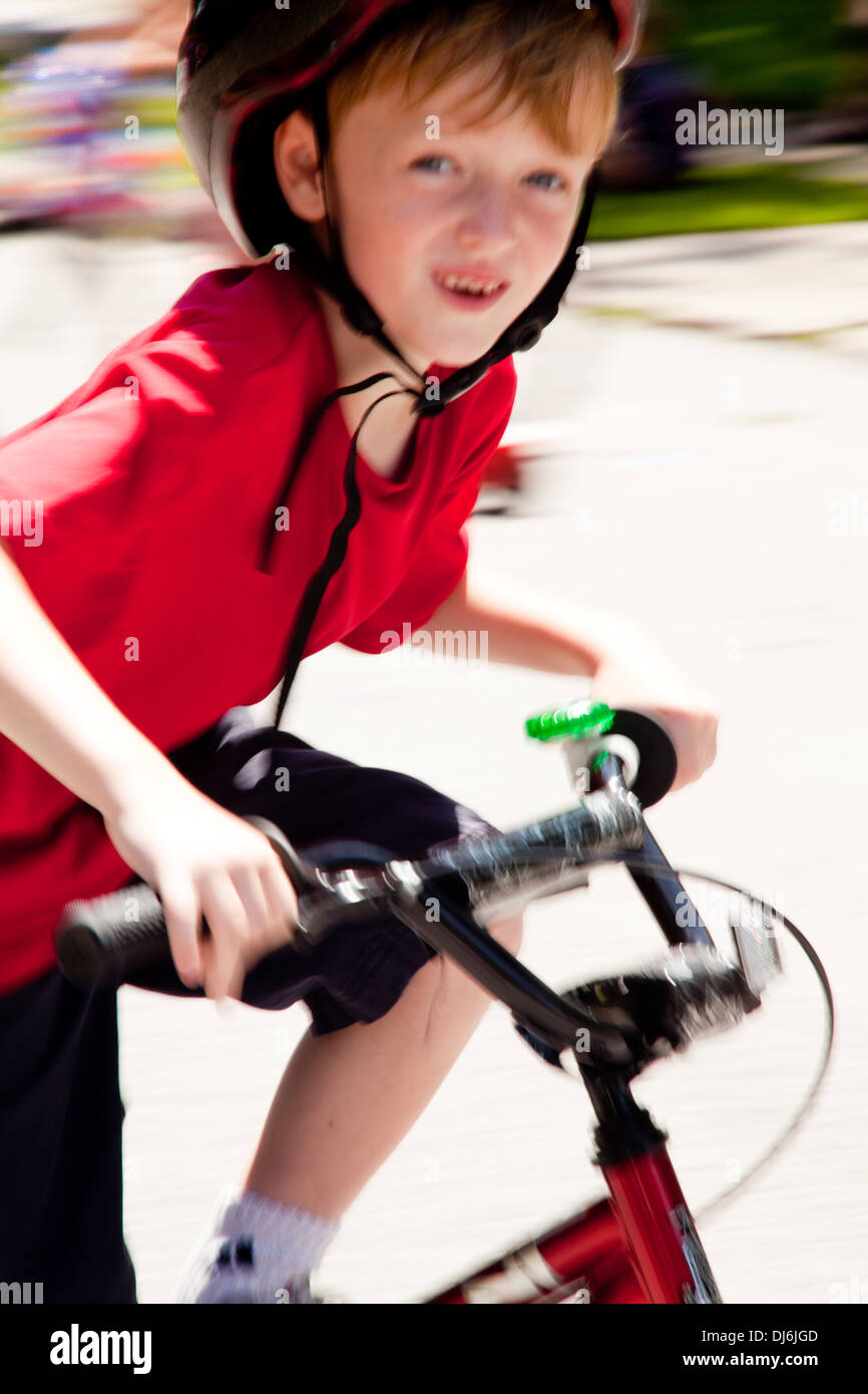 summertime boy riding bike - wearing helmet, background blur Stock Photo