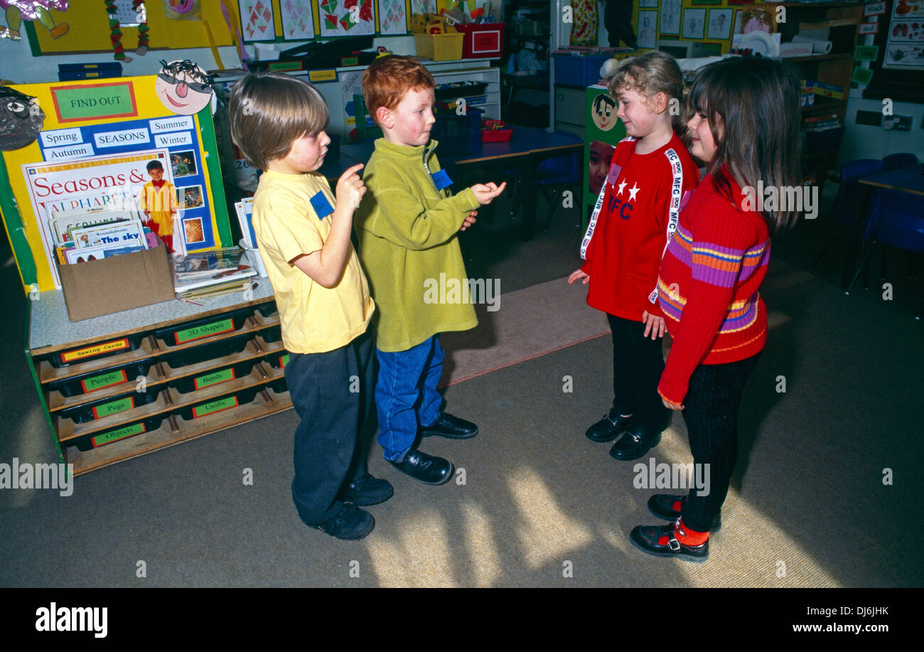 Two Girls & Two Boys In Classroom Talking Stock Photo