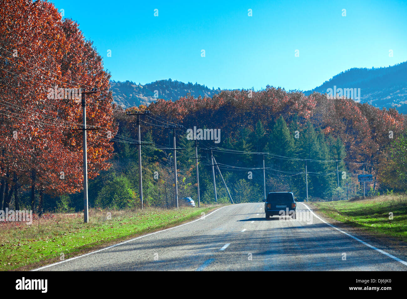 Car moving on the mountain road in autumn sunday Stock Photo