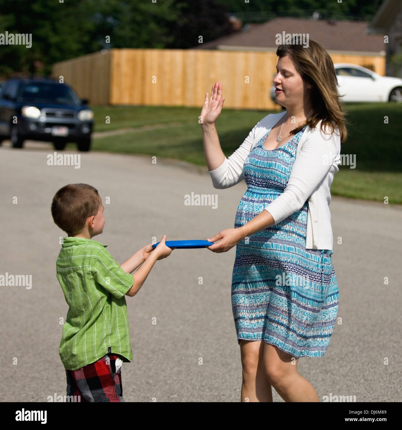 Pregnant Woman Giving a Frisbee to a Five Year Old Boy Stock Photo