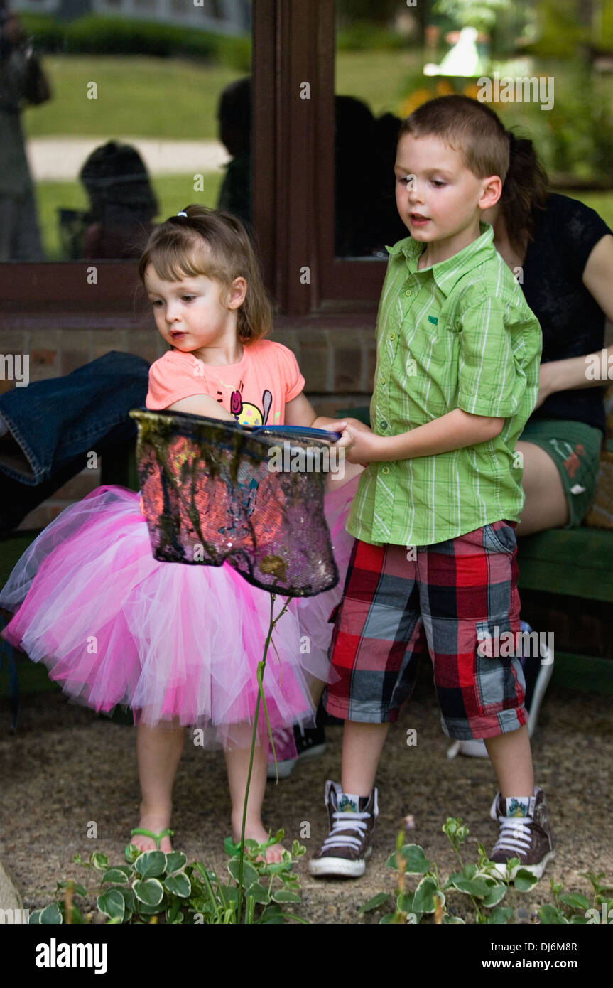 Three Year Old Sister and Five Year Old Brother Playing with Fish Net on Porch of Suburban Home Stock Photo
