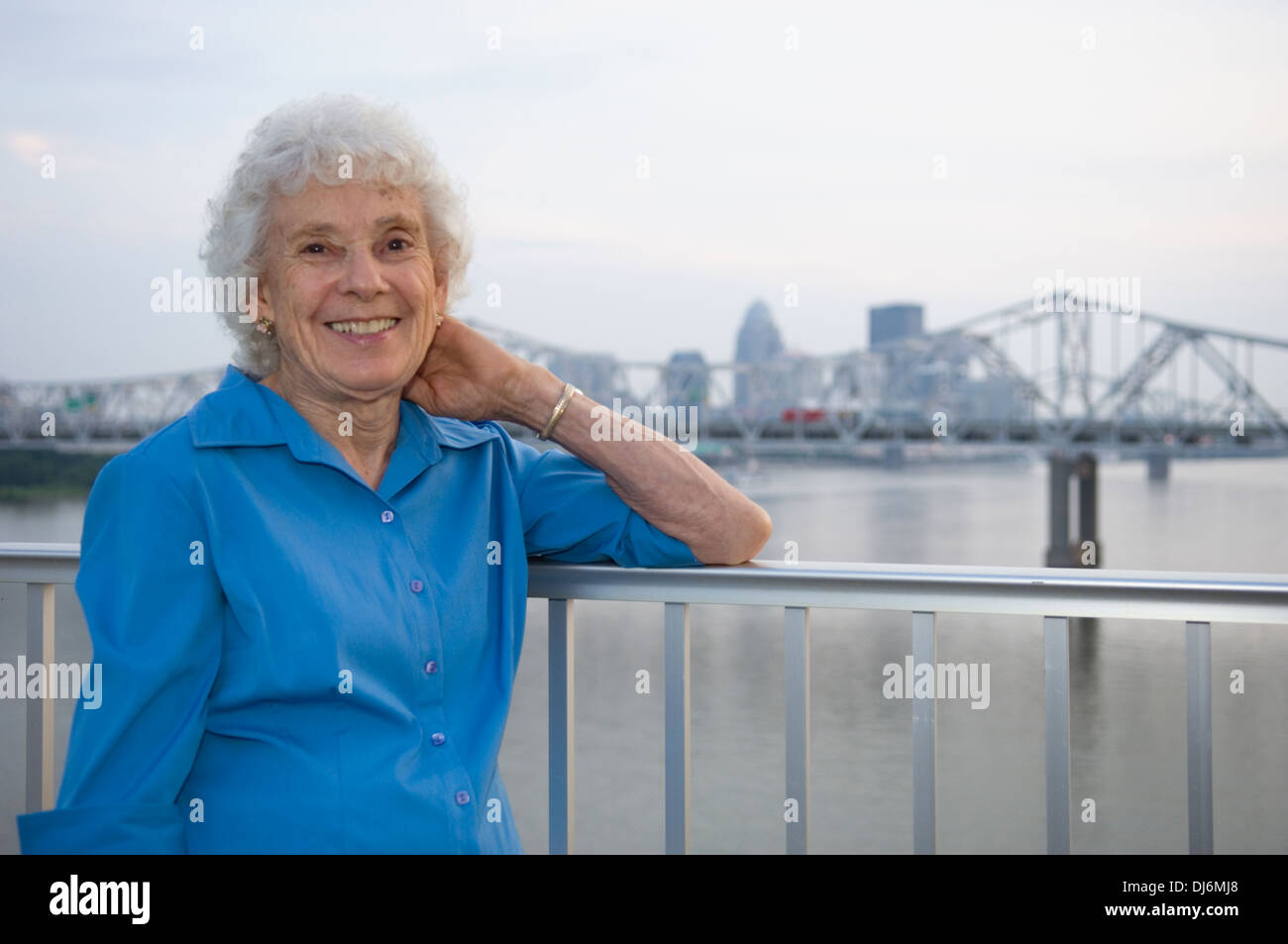 Senior Woman Posing for Photograph on the Big Four Pedestrian Bridge with Louisville Kentucky in the Background Stock Photo