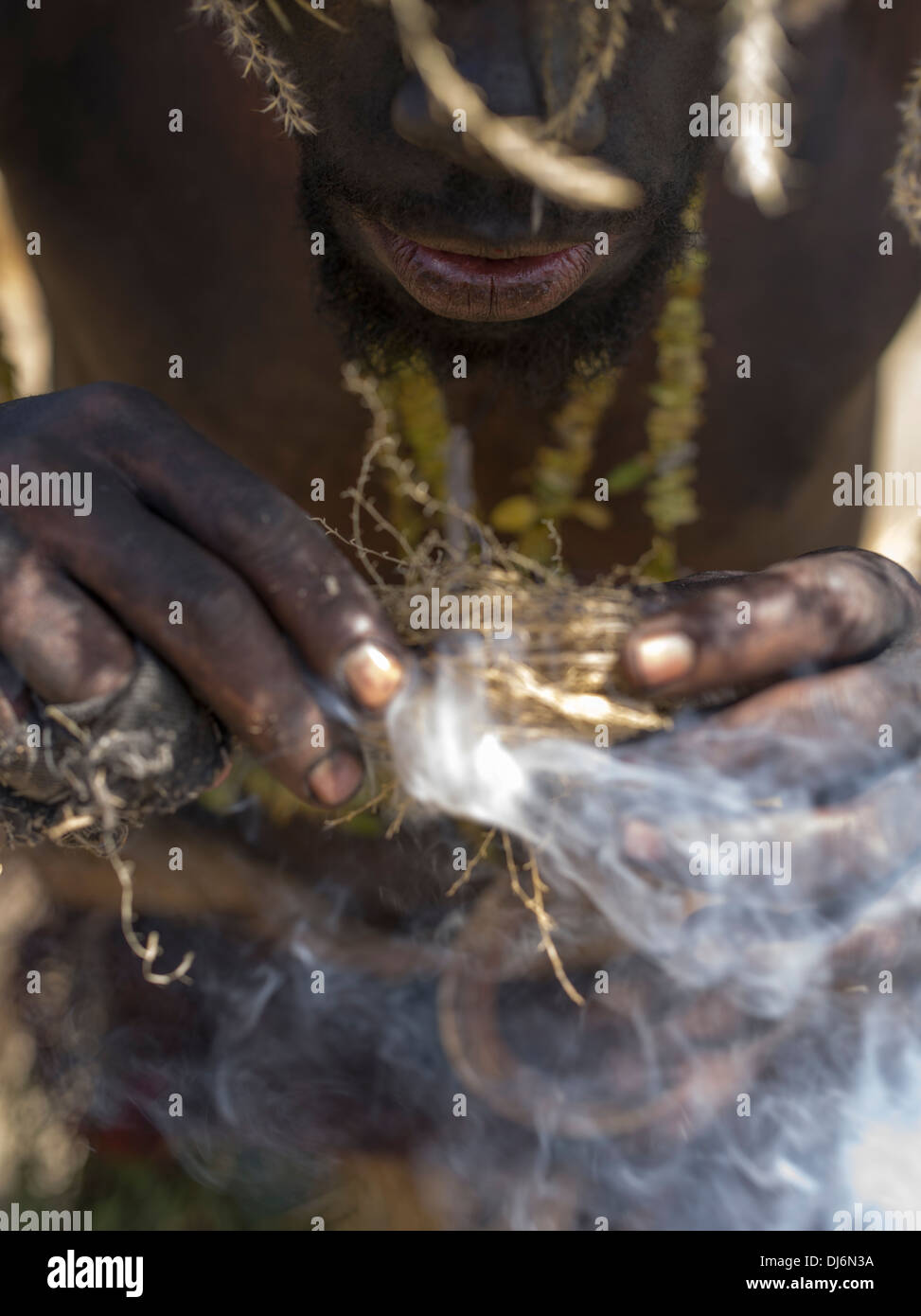 Traditional  fire starting  by blowing on smoldering embers, Papua New Guinea Stock Photo