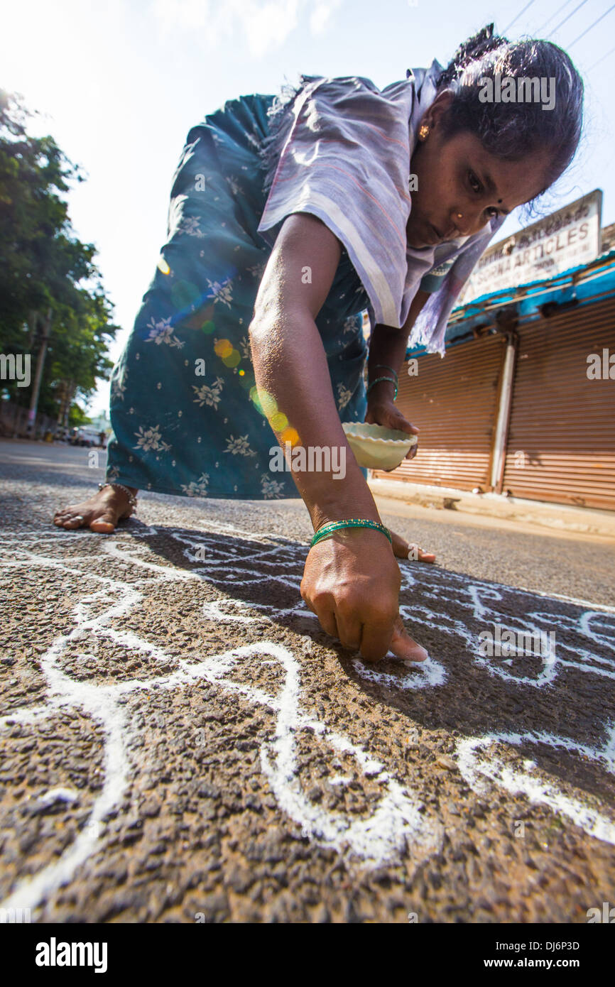 Woman drawing Hindu kolam treshold signs, Mahabalipuram or Mamallapuram, Tamil Nadu, India Stock Photo