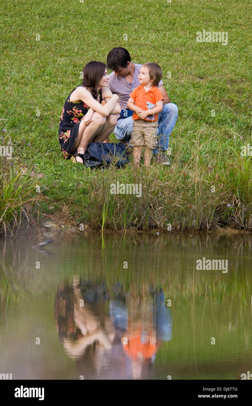Young Family Beside Pond Stock Photo