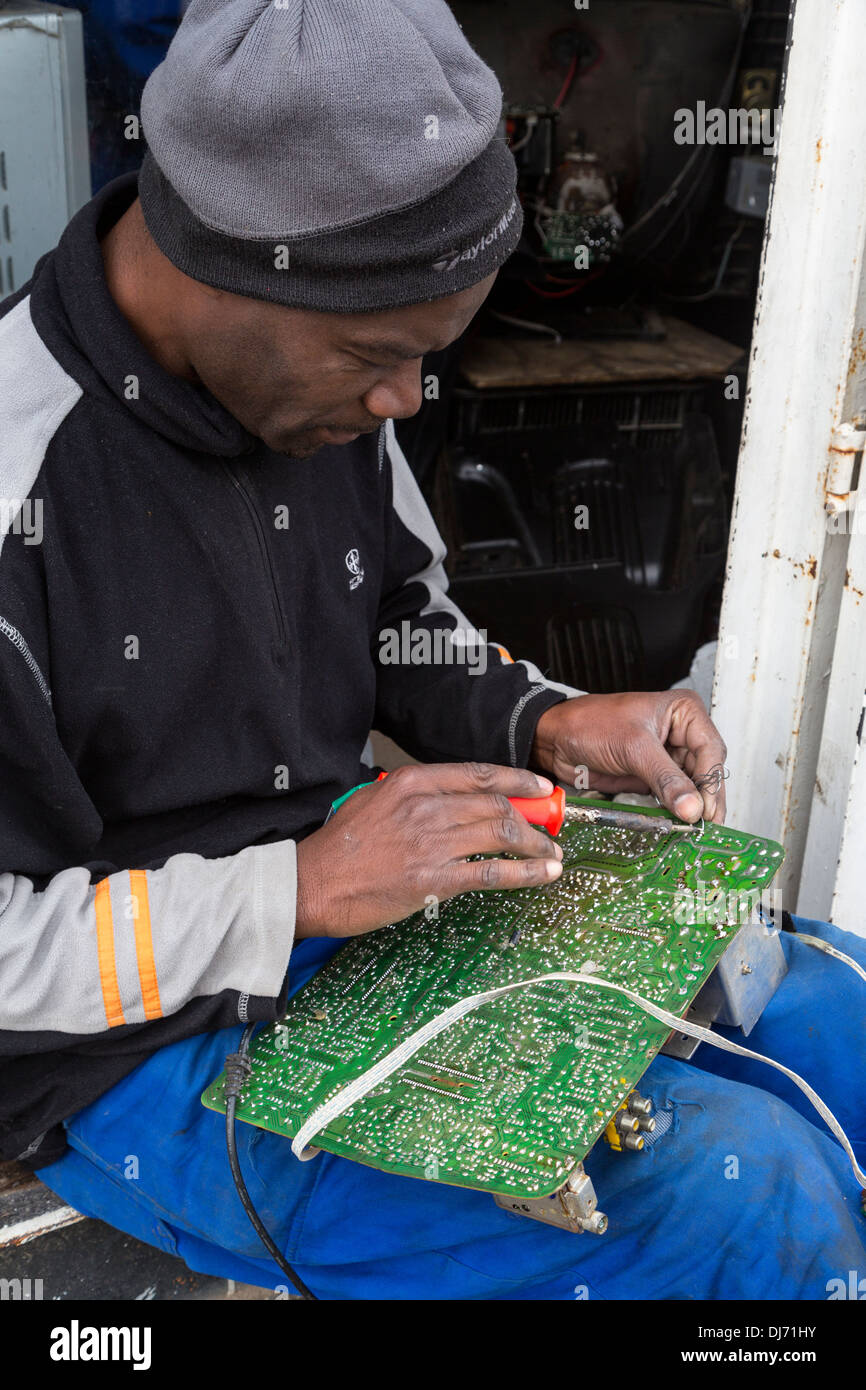 South Africa, Cape Town, Guguletu Township. Man Soldering a Circuit Board. Stock Photo