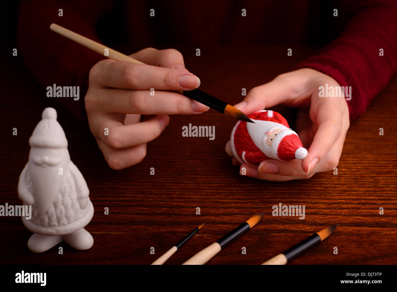 Christmas decorations: woman hands with porcelain figurine of Santa, painting, making of Christmas decoration Stock Photo