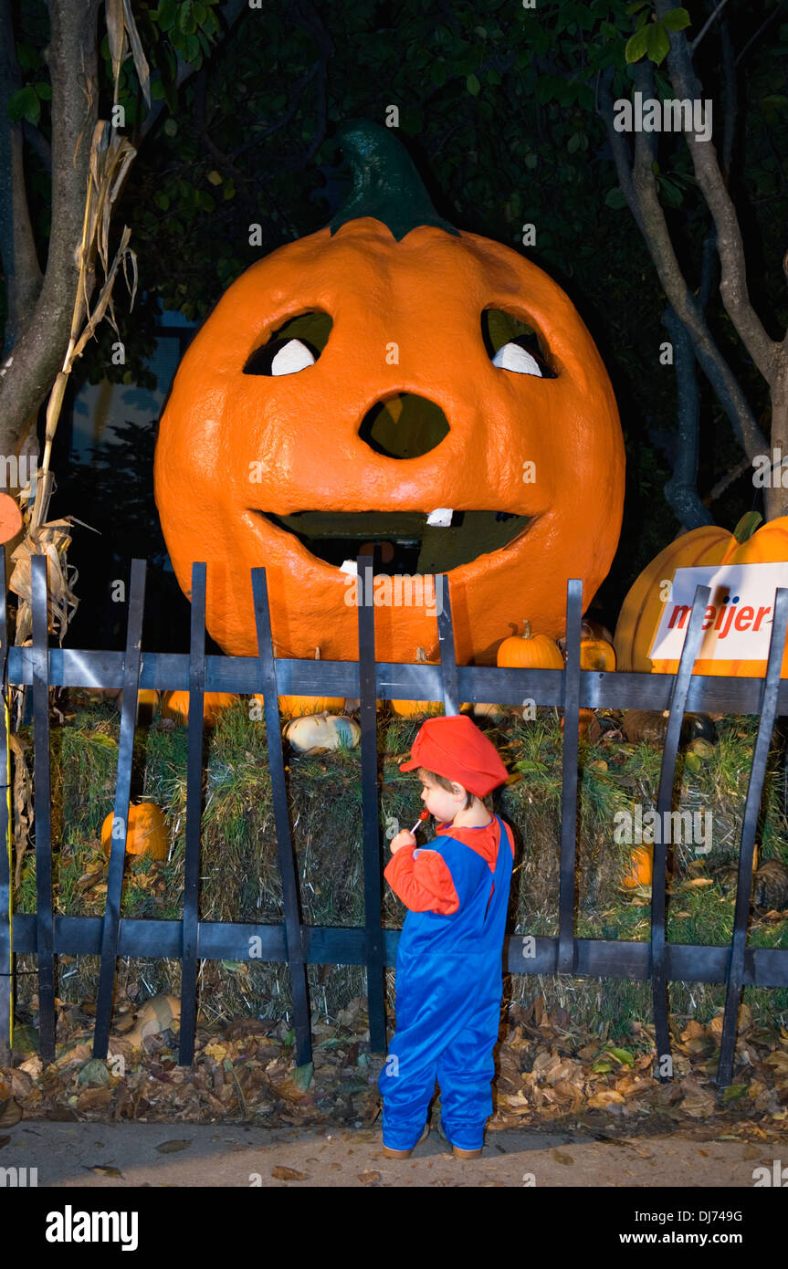 Toddler Dressed Up as Mario fStanding next to Giant JackOLantern at