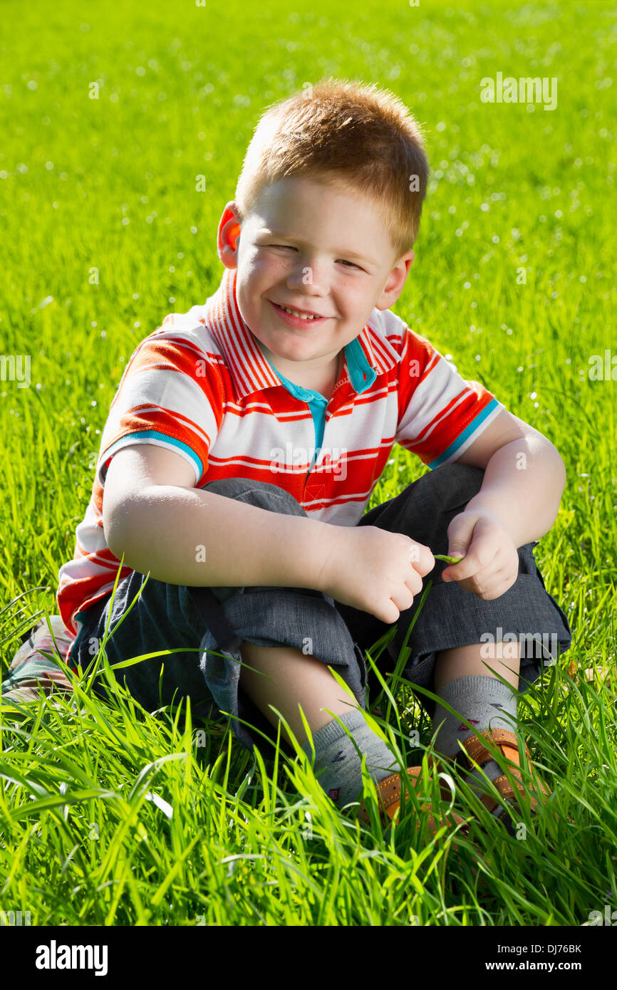 boy sitting on field of grass Stock Photo