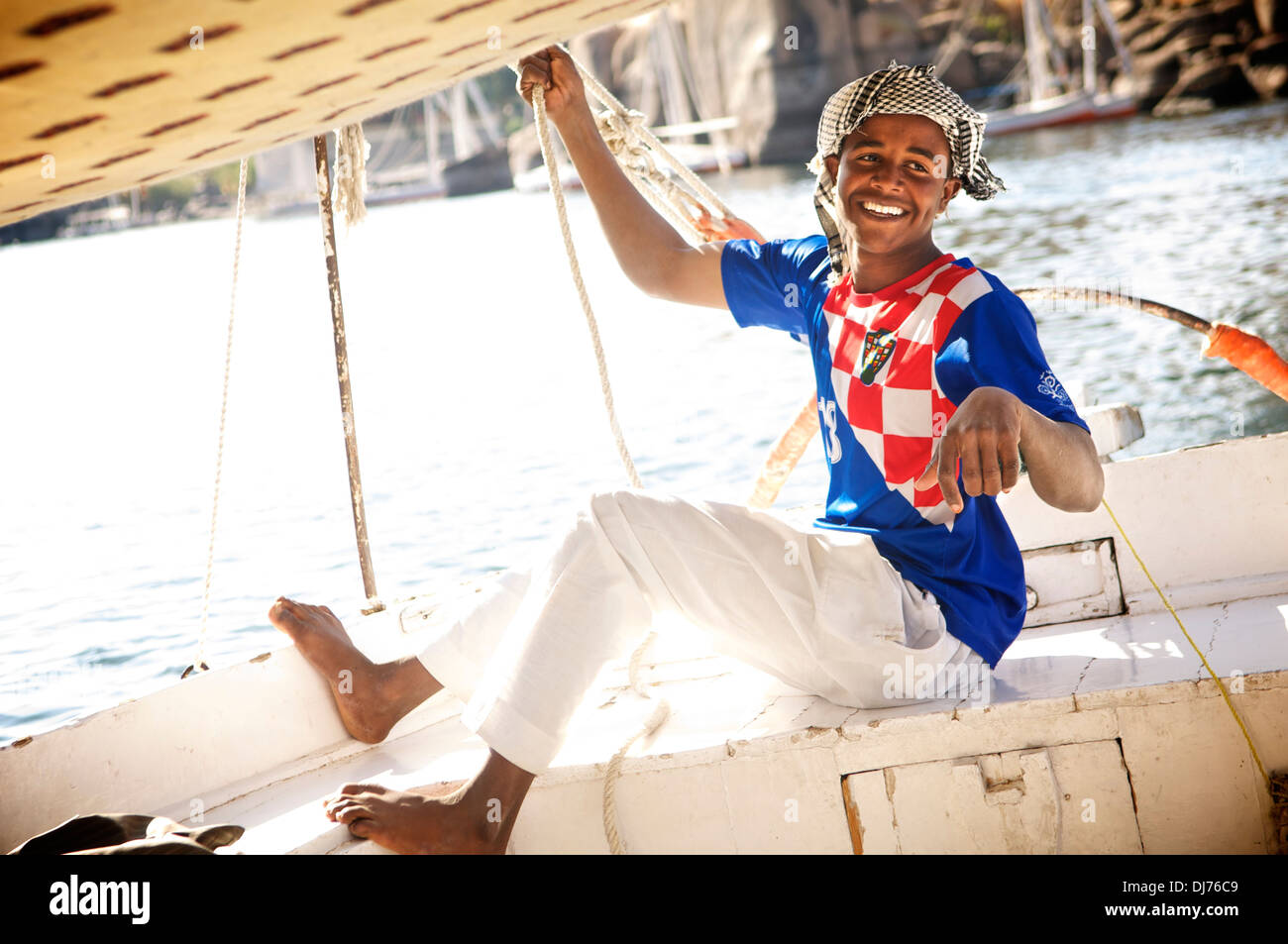 Young felucca pilot smiles while ably handling his father's boat on the Nile, at Aswan, Egypt. Stock Photo