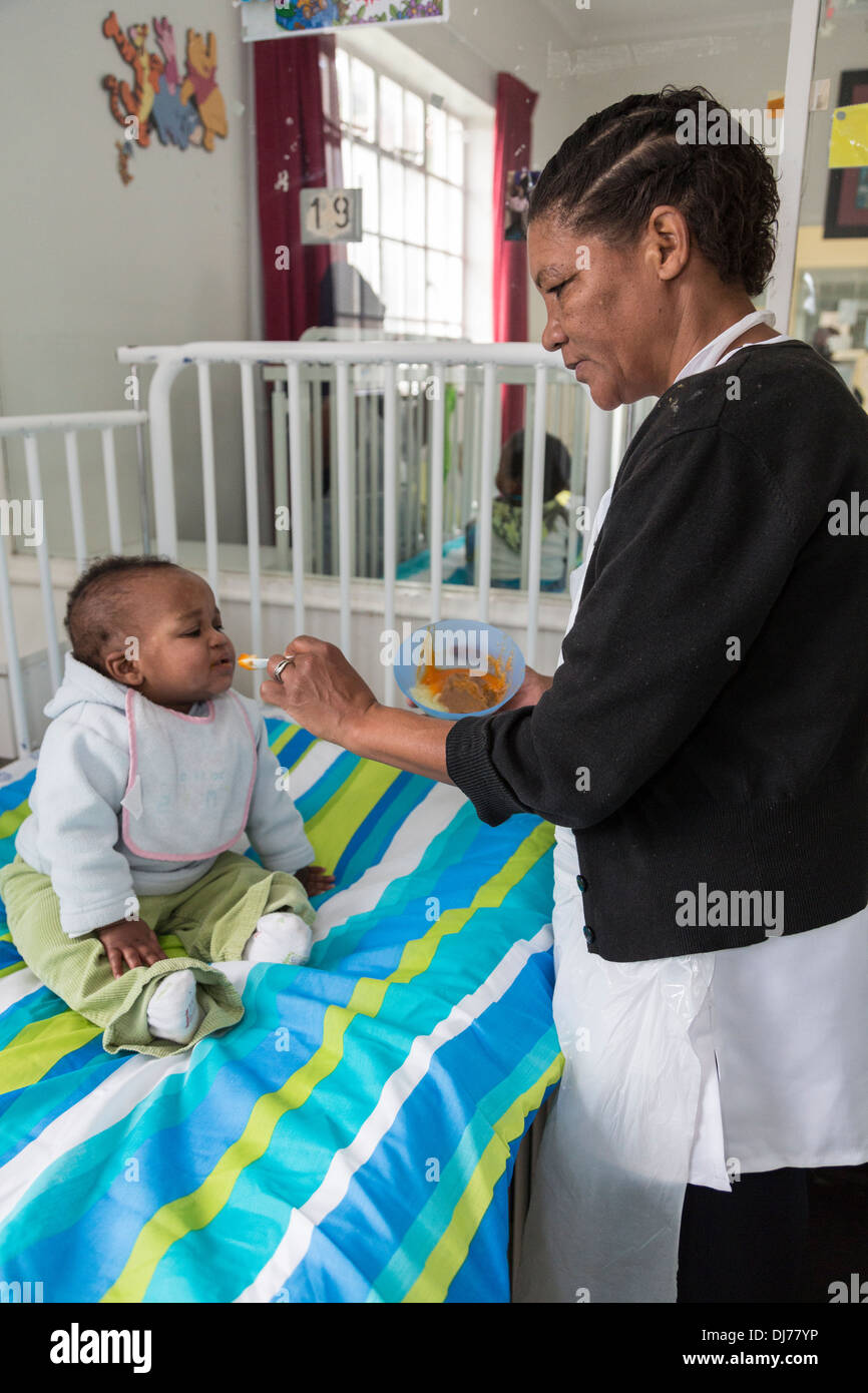 South Africa, Cape Town. Nurse Feeding Small Child in a Special Care Facility. Stock Photo