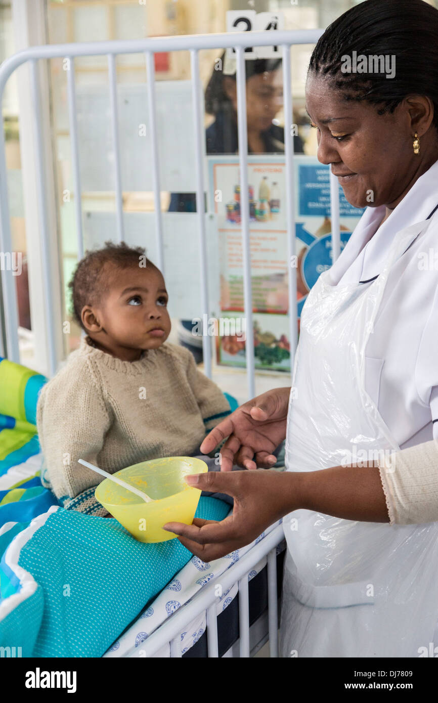 South Africa, Cape Town. Nurse Feeding Small Child in a Special Care Facility. Stock Photo