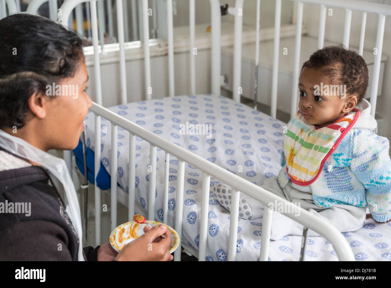 South Africa, Cape Town. Nurse Feeding Small Child in a Special Care Facility. Stock Photo