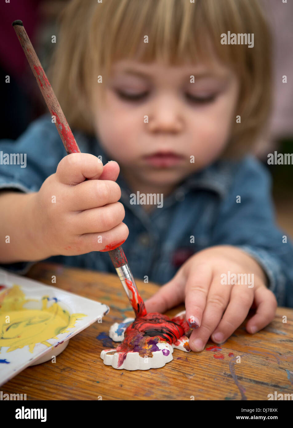 A small child painting a ceramic fridge magnet Stock Photo