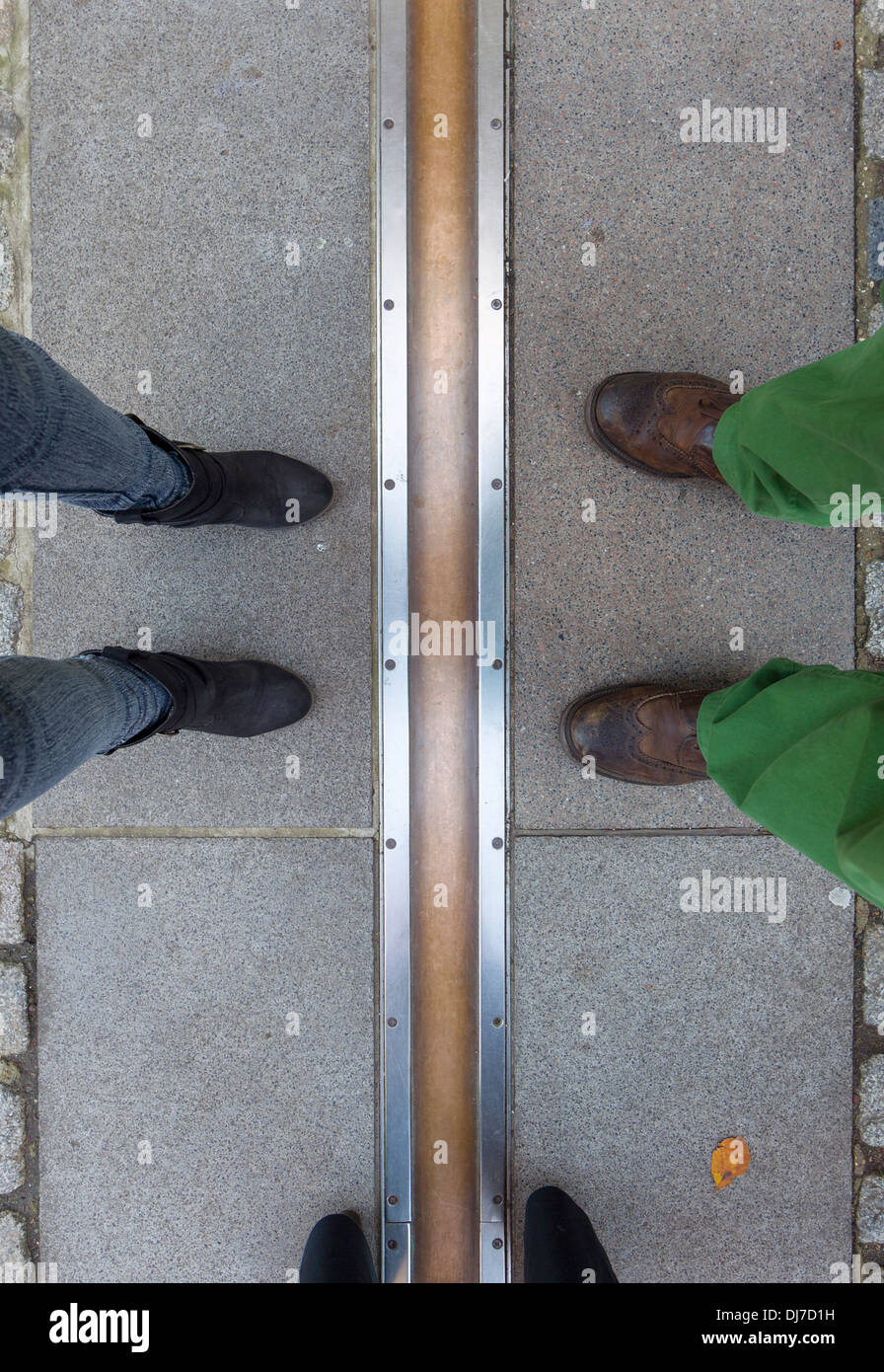 Three pairs of feet straddling (and standing either side of ) the Greenwich Meridian Stock Photo