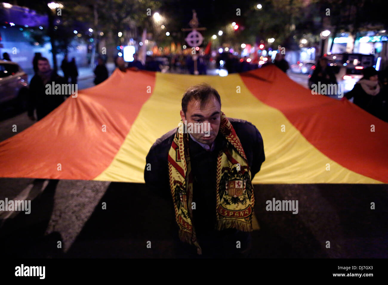 Madrid, Spain. 23rd Nov, 2013. A protester with a scarf with fascist symbology carry with the help of 6 more protesters a huge spanish flag as they march to el valle de los caidos.The march takes place from Madrid to the Valley of the Fallen where the tombs of Spain's former dictator Gen. Francisco Franco and Primo de Rivera lie in its 77th anniversary. Credit:  Rodrigo Garcia/NurPhoto/ZUMAPRESS.com/Alamy Live News Stock Photo