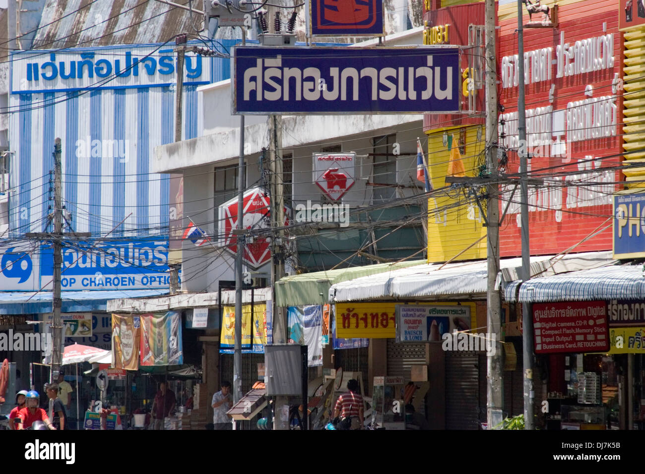 Many signs written in Thai are part of the urban landscape above a city street in Khon Kaen, Thailand. Stock Photo