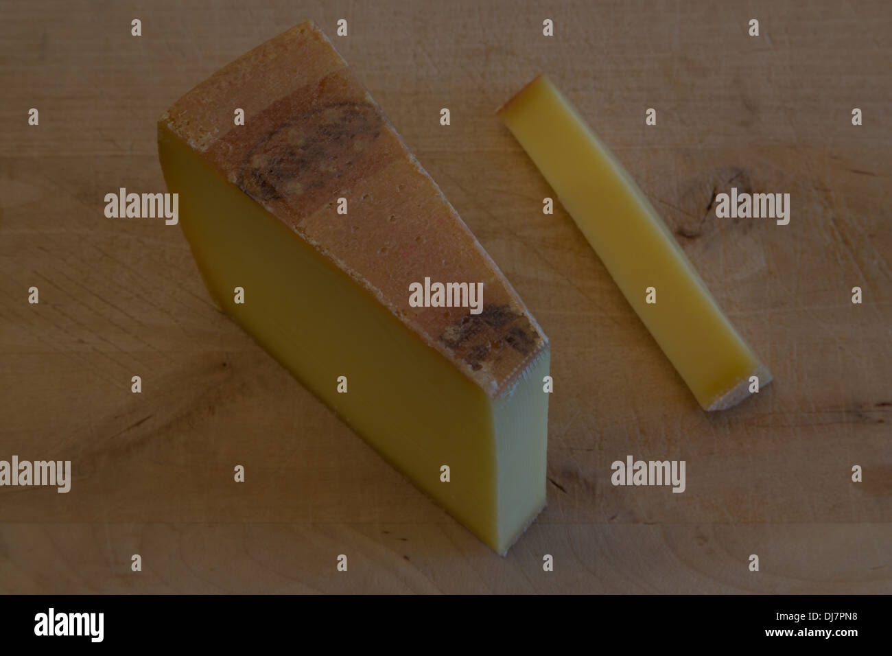 A photograph of some Swiss cheese on a wooden cutting board. It is Gruyere cheese and not the Swiss cheese most people think of. Stock Photo
