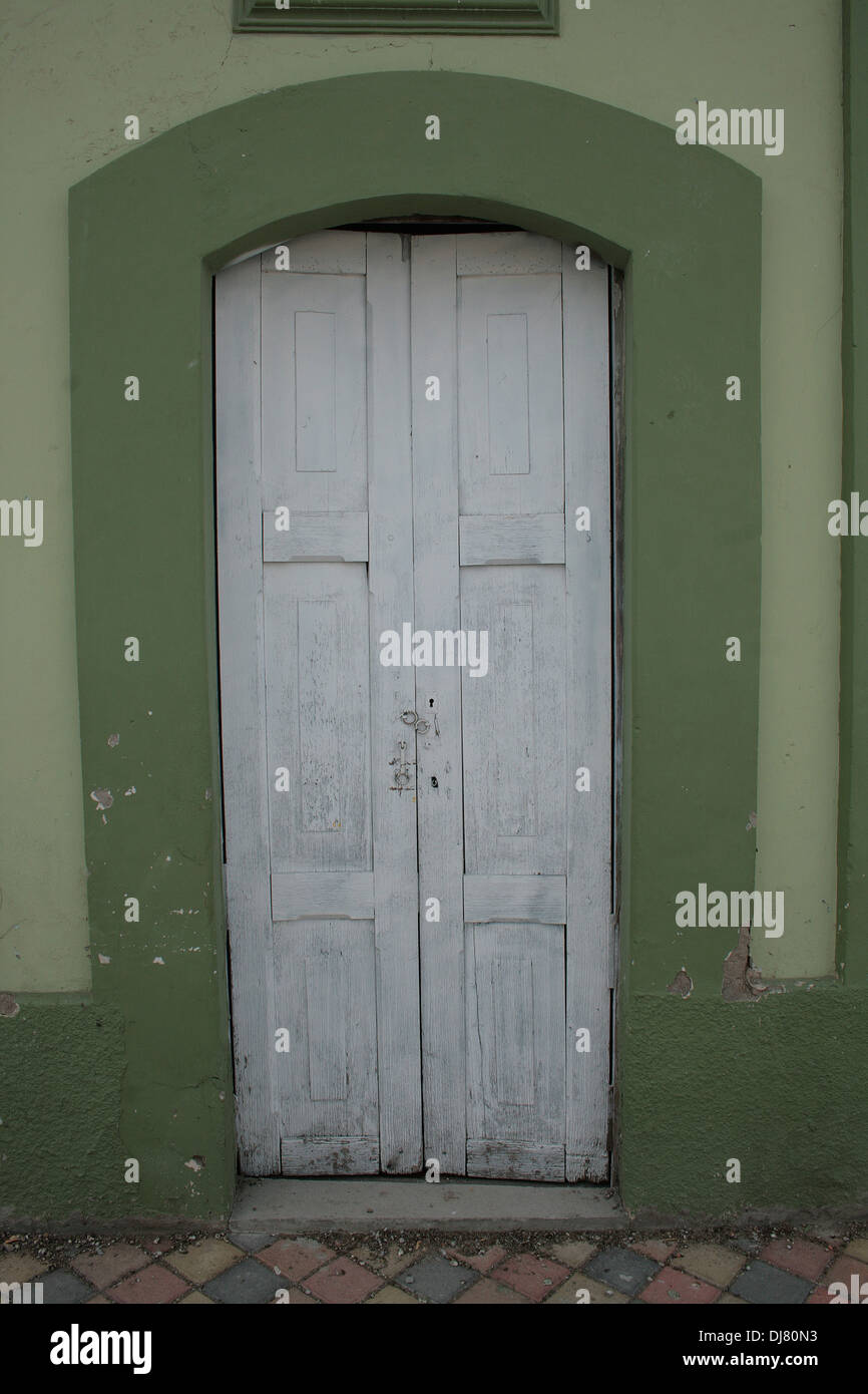 A white wood door set in the green wall of a building in Cotacachi, Ecuador Stock Photo