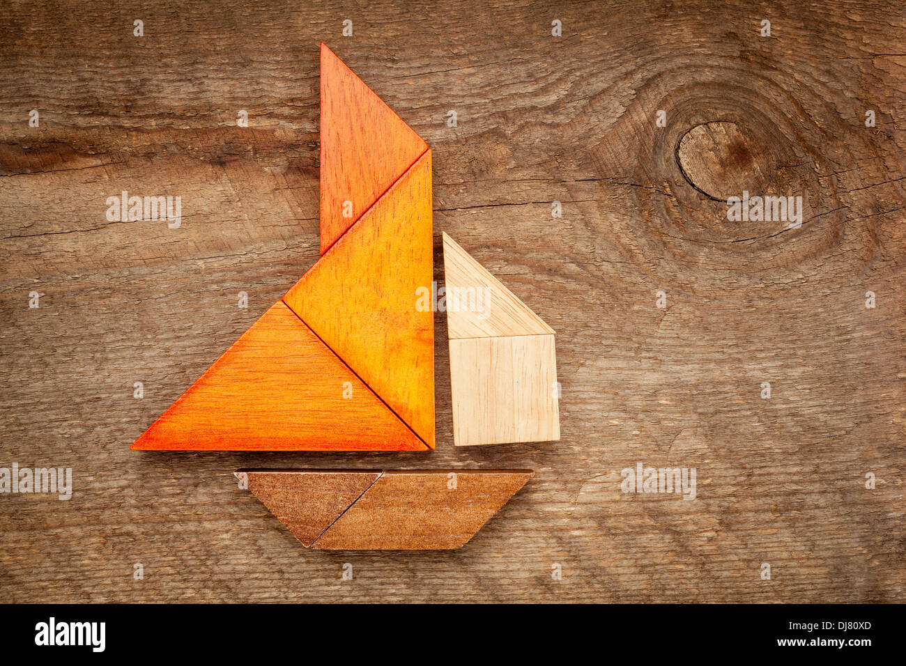 abstract picture of a sailing boat built from seven tangram wooden pieces over a rustic barn wood, Stock Photo