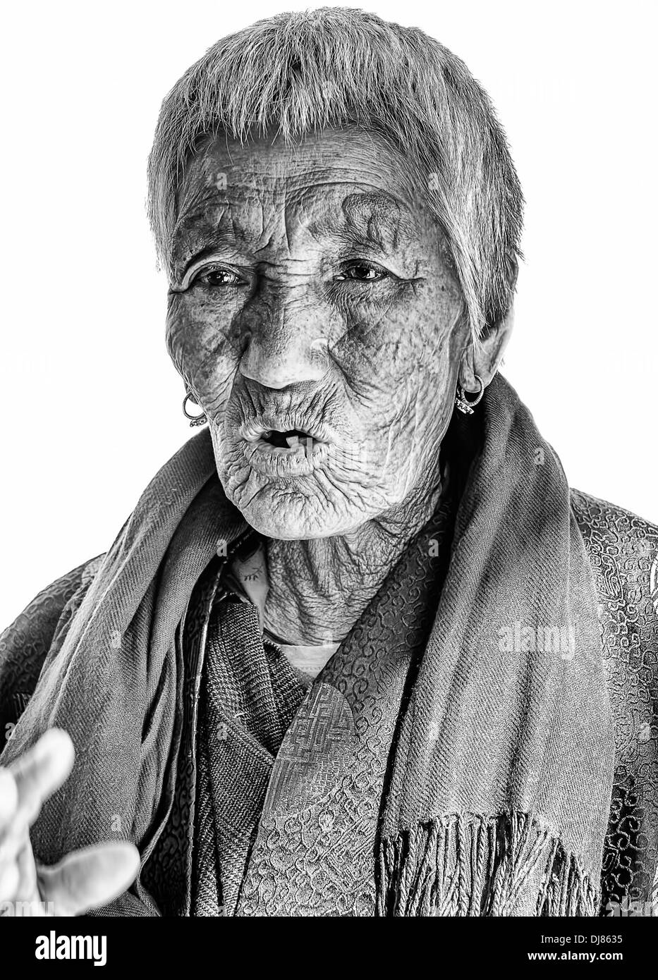 Bhutanese Old Lady in prayer dress isolated on white in black and white with copy space Stock Photo