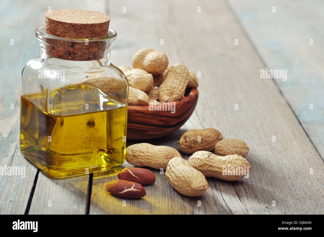 Peanut oil with raw peanuts on wooden background Stock Photo