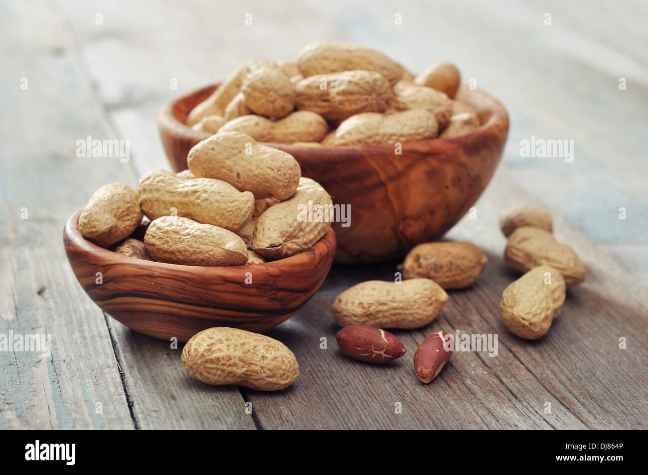Unpeeled peanuts in bowl on wooden background closeup Stock Photo