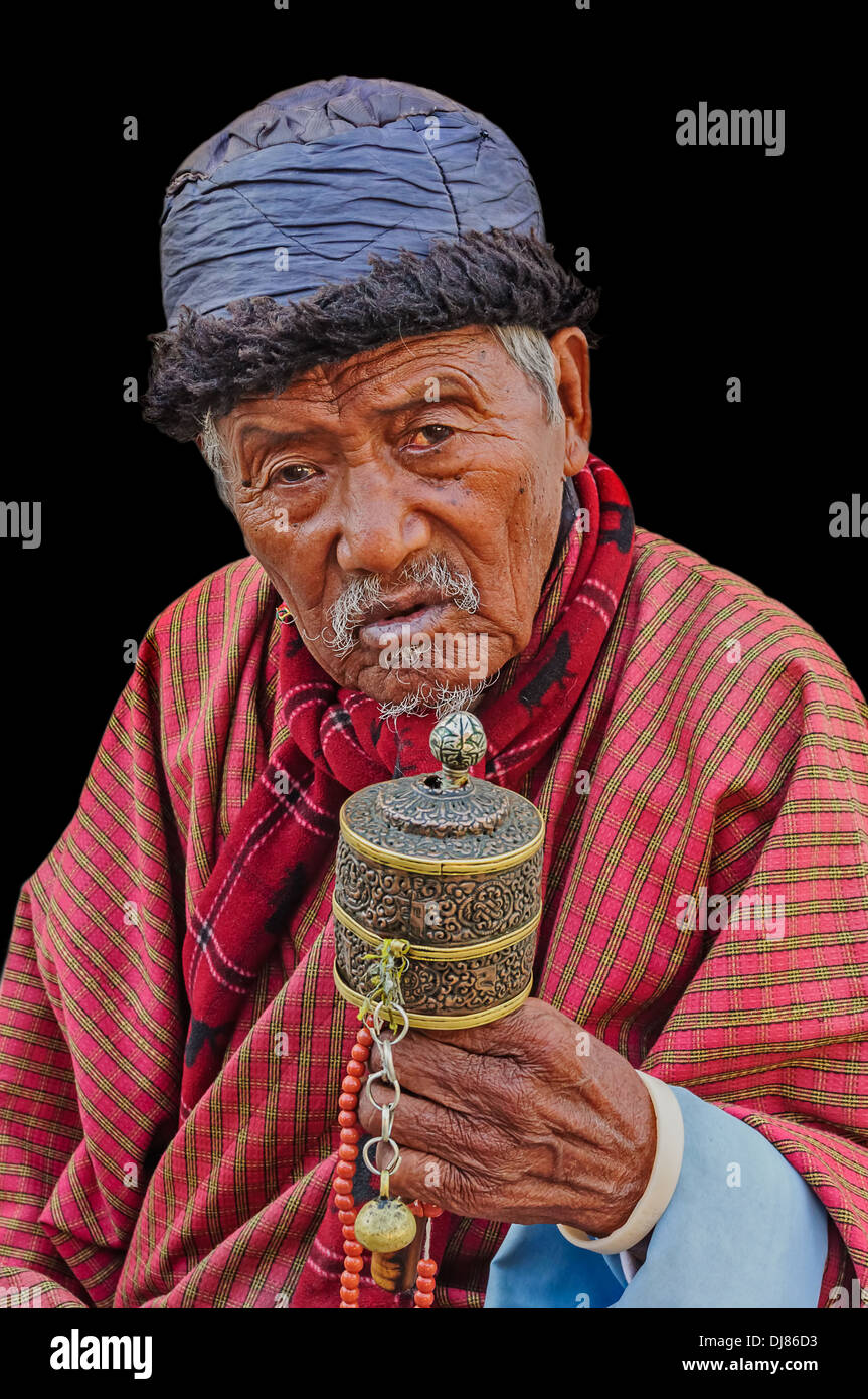 Old Bhutanese Buddhist man praying isolated on black background Stock Photo