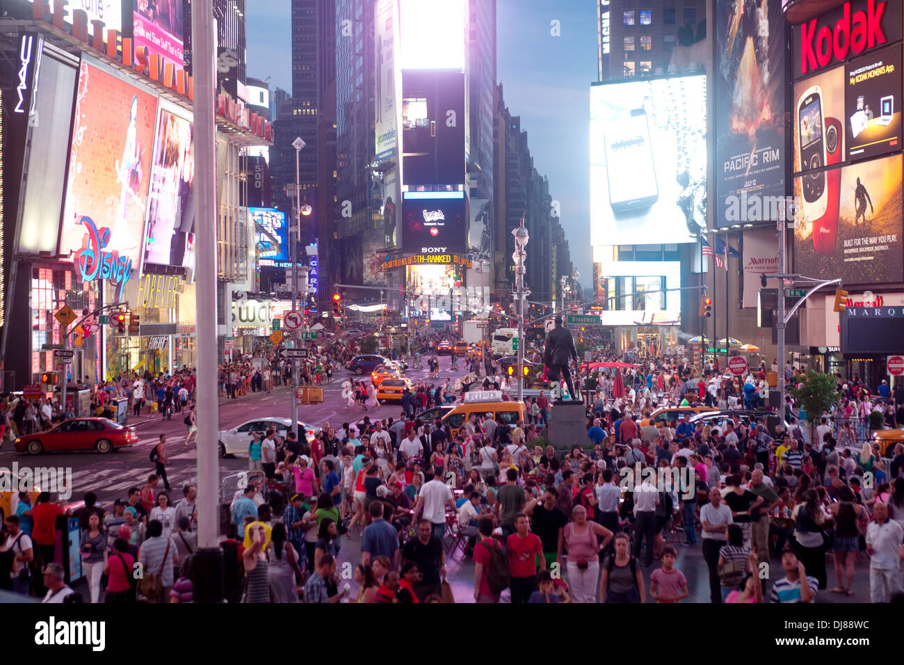 A crowd of people gather under the neon signage in Times Square, New York City at night. Stock Photo
