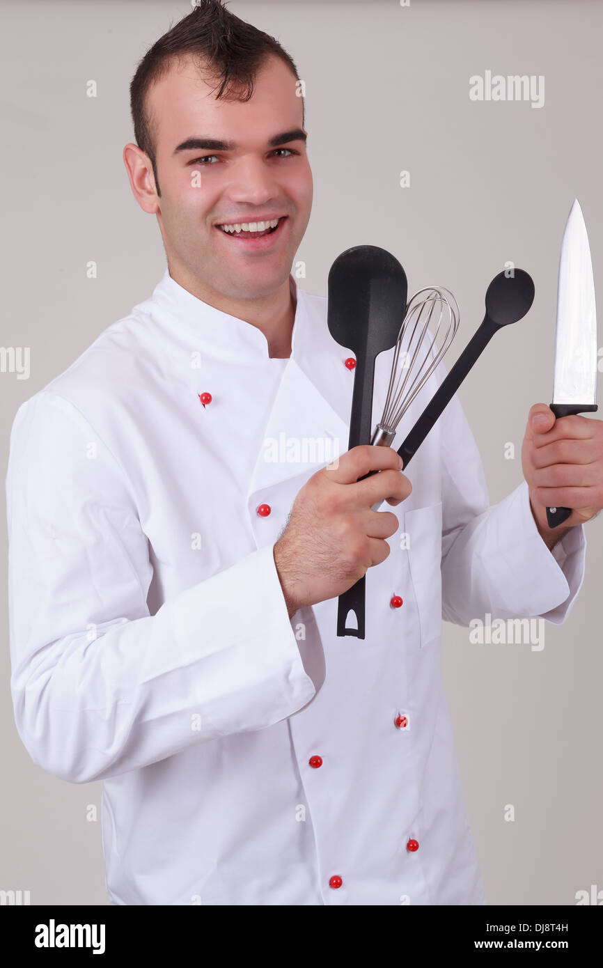 Happy chef holding various kitchen utensils Stock Photo