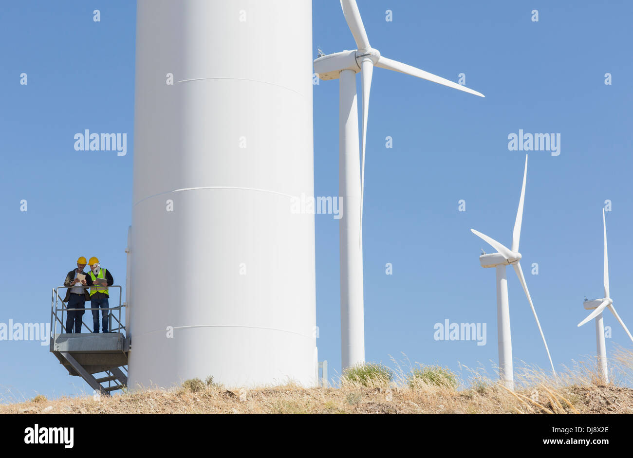 Workers talking on wind turbine in rural landscape Stock Photo