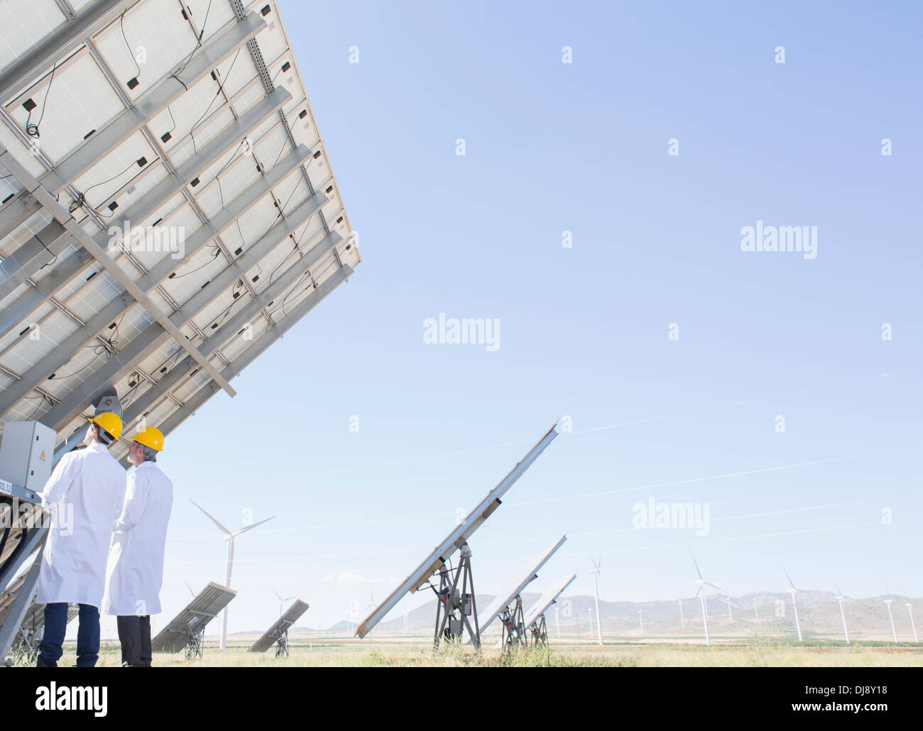 Scientists examining solar panel in rural landscape Stock Photo