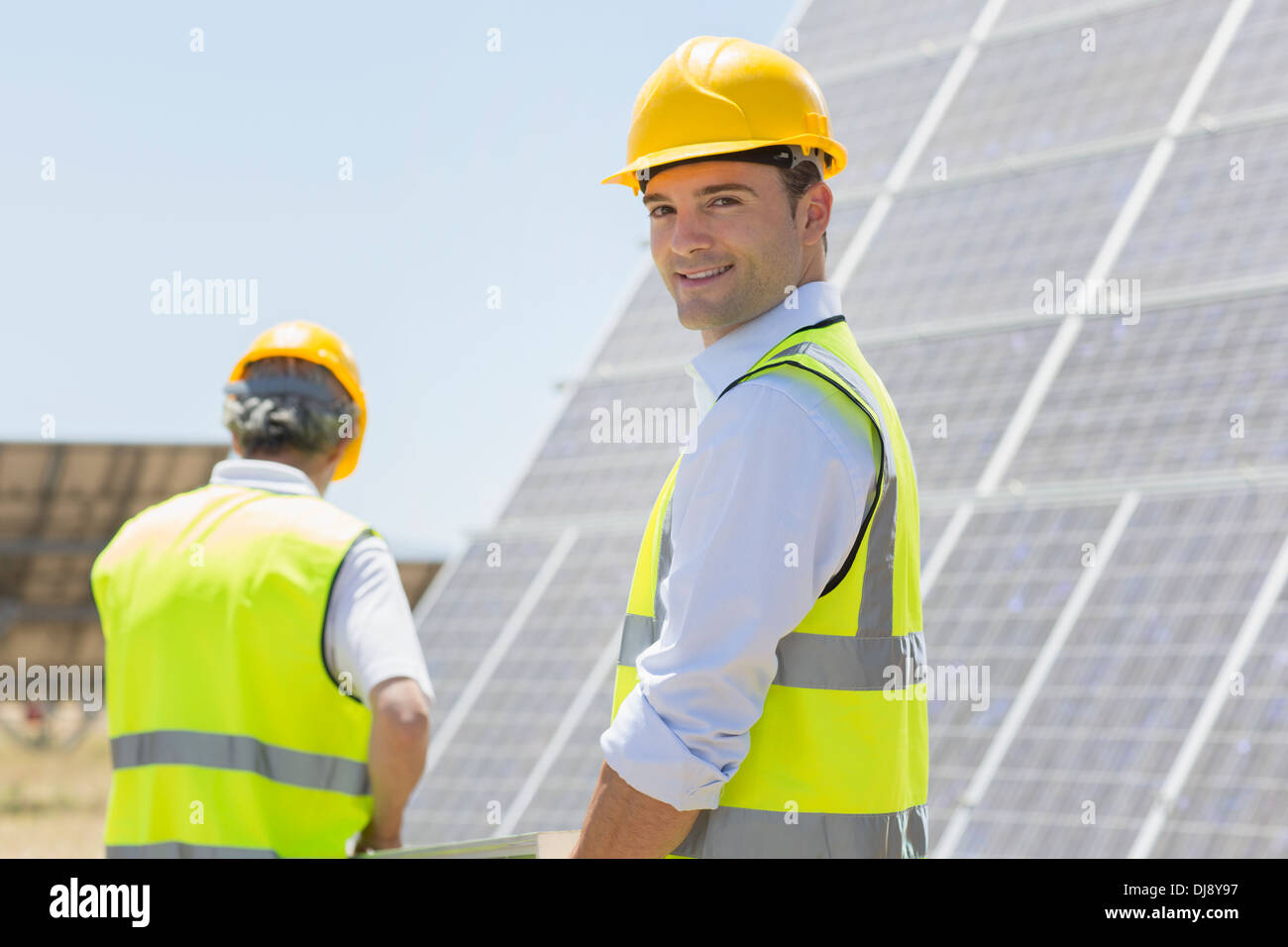 Workers walking by solar panels in rural landscape Stock Photo