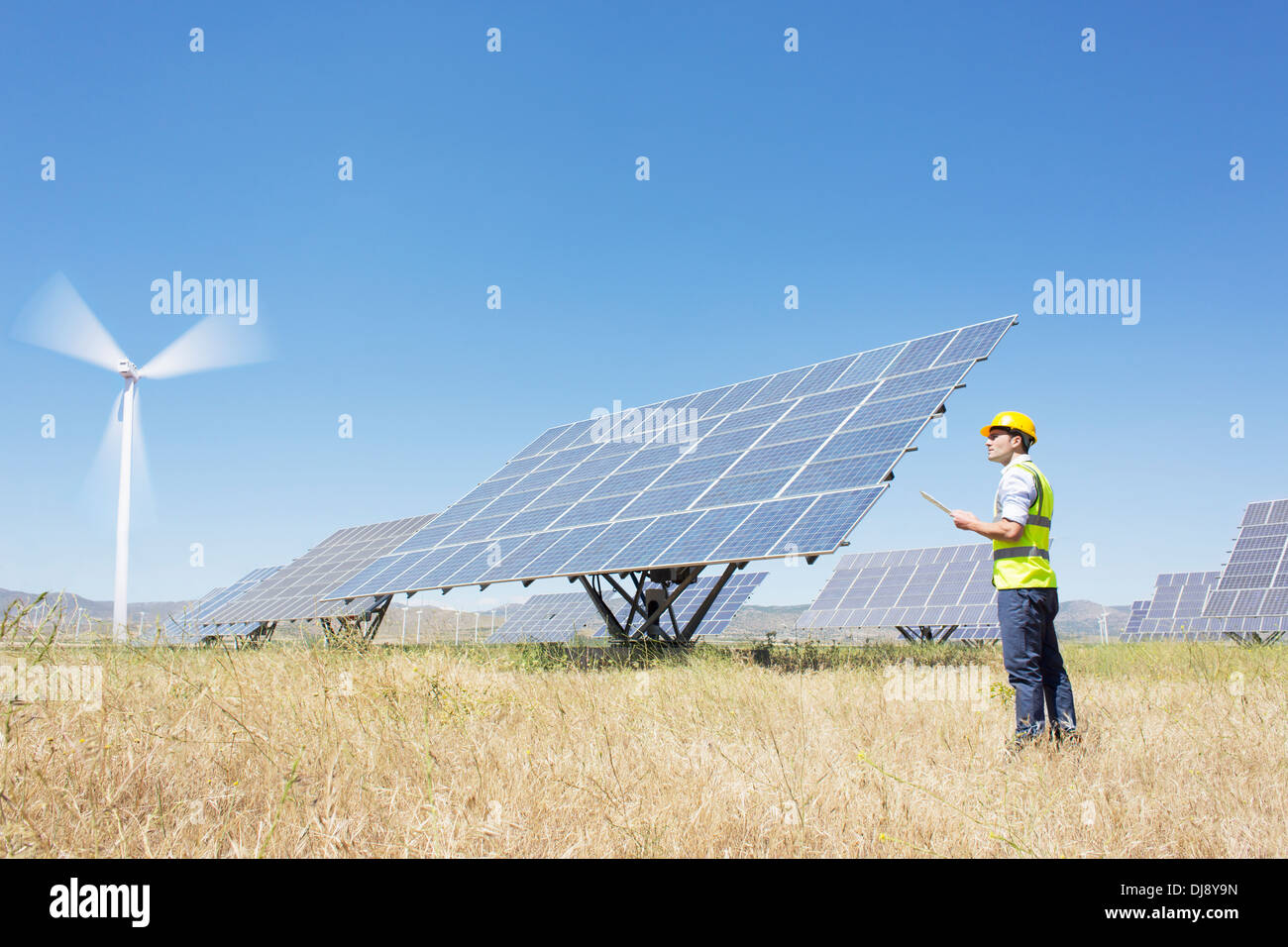Worker examining solar panels in rural landscape Stock Photo